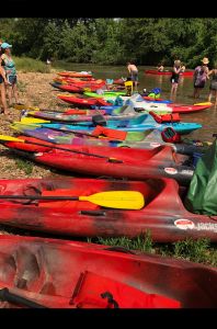 Different colors of Kayak Boats on the shore. Different people chatting with each other on shores and in water